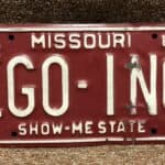 A maroon colored license plate from Missouri spells out the words "ego inc" in white letters.