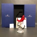 A Swarovski crystal figurine featuring a red fish twisting upward stands in front of its original blue box.
