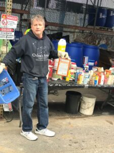 Chris Lancette, a middle-age man with brown and gray hair wearing a black Orion's Attic hoodie, properly disposes of chemicals in the environmentally conscious way -- at the Montgomery County transfer station.