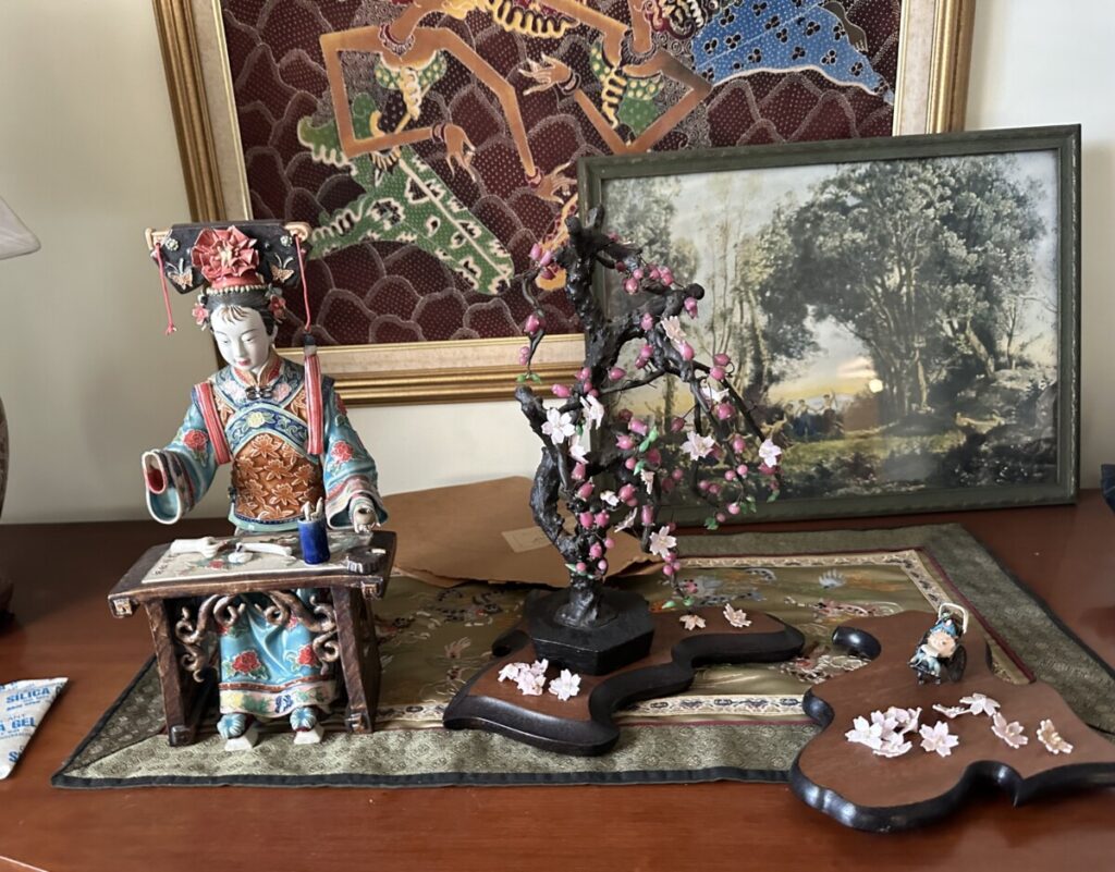 A Japanese porcelain figurine sits next to a figure of a lotus flower.