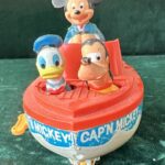 A plastic windup Mickey Mouse boat with Mickey as captain and Goofy and Donald Duck as passengers.