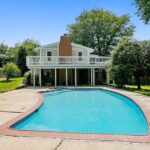 A large swimming pool sits behind a Silver Spring two-story home with patio deck.