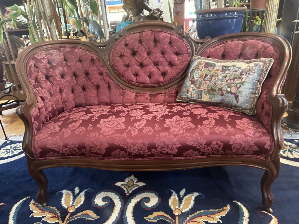 An antique settee in red upholstery sells for little today.