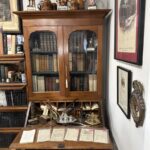 An antique secretary desk with two glass doors covering the book cabinet.