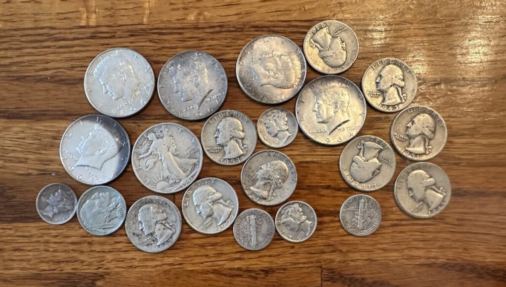 A group of American coins from 1964 and earlier is spread out out a table.