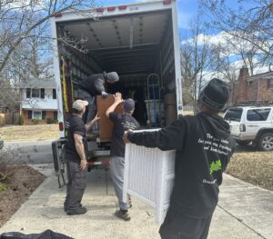 Three Orion's Attic crew members wearing black hoodies load a pair of dressers onto a Community Forklift truck for donation. 