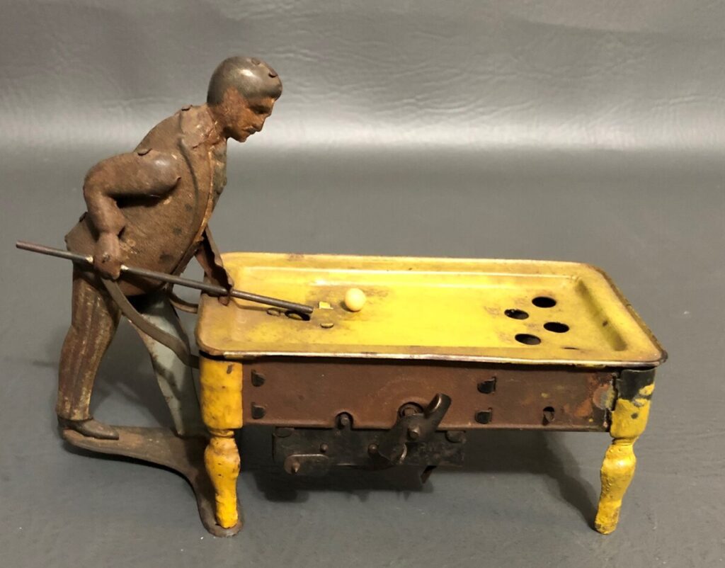 A vintage German windup tin toy features a man shooting pool.