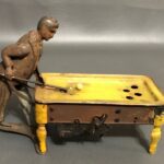A vintage German windup tin toy features a man shooting pool.