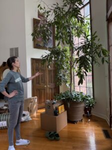 Client Kristen stands to the left of a tree growing in a pot inside the giant house.