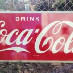 A vintage, horizontal Coca-Cola sign.