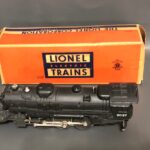 Lionel train engine sits in front of class orange box.