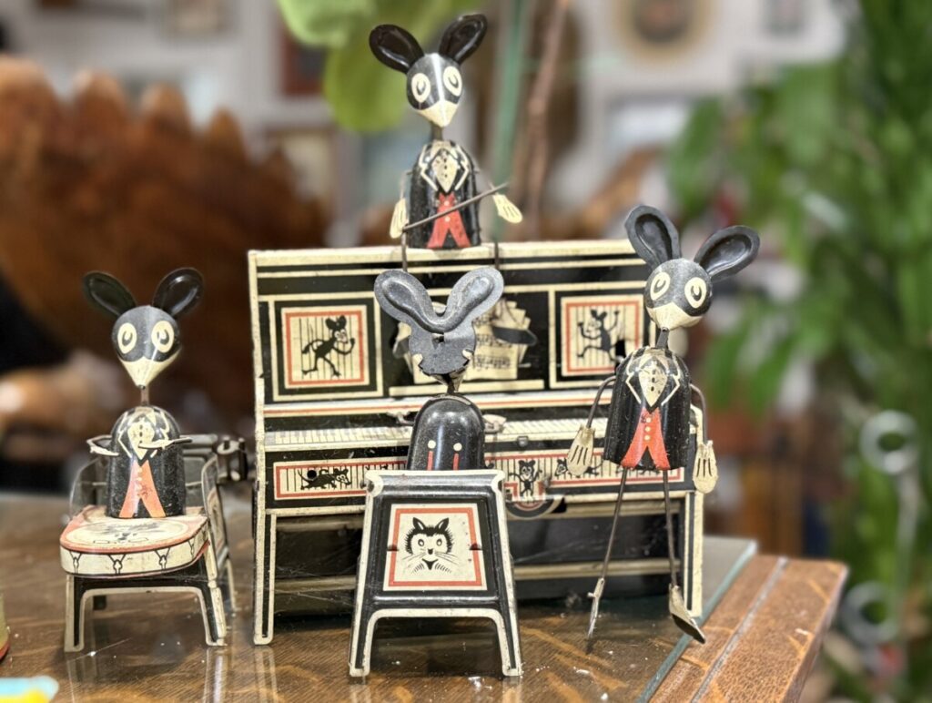 This Louis Marx Merrymakers tin windup toy features one mouse playing a piano, another playing the drums, and another sitting atop the piano.