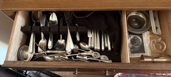 A drawer full of random sterling silver flatware sits unused.