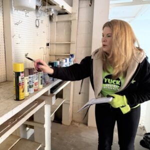 Raea Jean Leinster of Yuck Old Paint inspecting aerosol paint and chemical cans during household hazardous waste removal.
