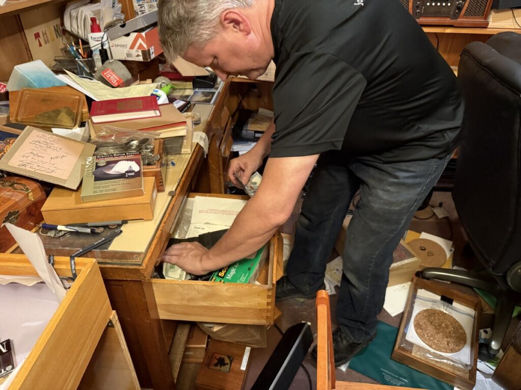 Chris from Orion’s Attic searching a desk drawer while finding cash during an estate cleanout.