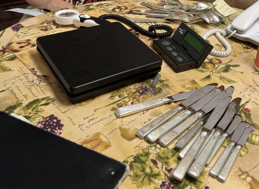 A kitchen table full of sterling flatware, a scale and magnifying glass -- what we need to help people sell sterling flatware.
