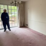 A happy senior citizen stands in her now empty den after our Silver Spring downsizing and home cleanout service.