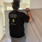 A worker from Orion's Attic wearing a company "green choice" t-shirt carries a mattress out of a home.
