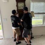 Orion's Attic moving crew move a grandfather clock to its new spot.